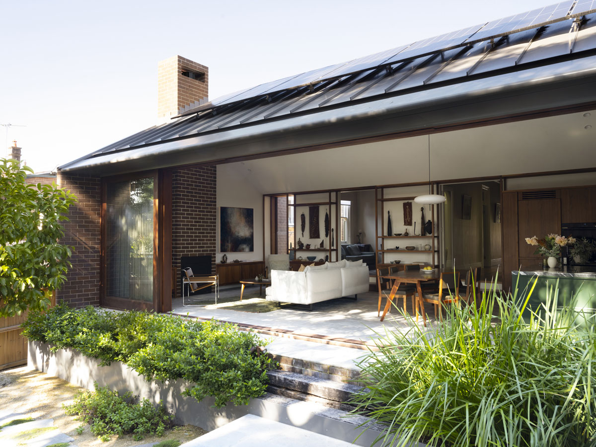 The rear of a single-family home. Large sliding doors open an interior living space out to a patio area.