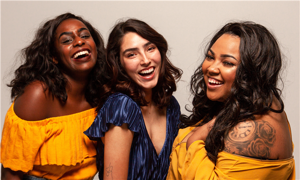 Three women in a group smiling and laghing, wearing bright yellow and blue shirts