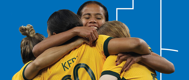 Three women in yellow soccer jerseys empbrace