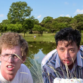 Two people with comical facial expressions outdoors with a lake in the background