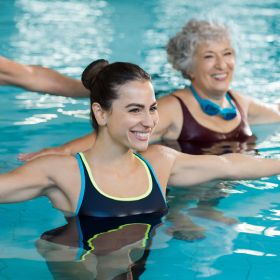 Two smiling people exercising in a pool