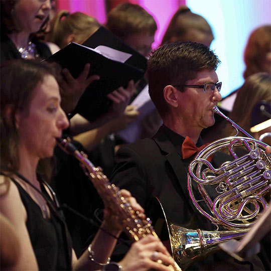 A flautist, a singer and a French horn player in performance.