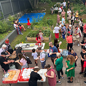 Aerial photo of people outdoors lining up and enjoying food at a community garden