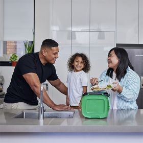 family putting food scraps into a small green lid bin