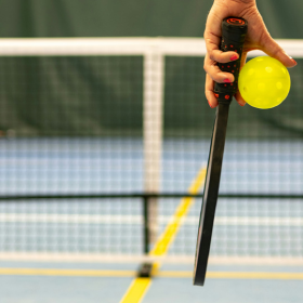 Close up of hand holding a racquet and ball