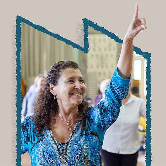 An older person smiling while holding a dance pose.