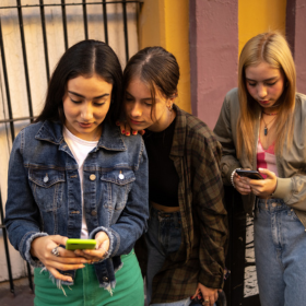 Three young women looking at their phones