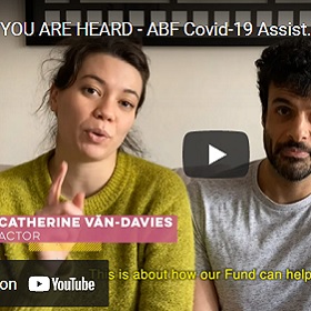 A screenshot of a youtube clip from the Actors Benevolent Fund, photo shows a cropped image of two actors talking to the camera, one on the left side wears a mustard colour jumper and is talking with hands and mouth, she wears her hair pulled up. The other actor wears a grey tshirt and has short dark hair and facial hair. The clip had white writing across the top of the screen which says: You are heard, ABF Covid-19 Assist. the youtube logo is in partial view on the bottom left of image. 