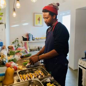 Man in kitchen in beanie preparing food