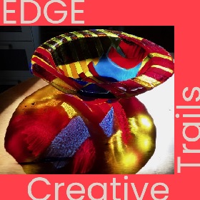 MaguraGlass EDGE Creative Trails promotional image of a beautiful glass bowl, light captures the bowl and the patterns and colour of the bowl are refelcted on the surface the bowl sits on, there are blue, red and and yellow geometric shapes