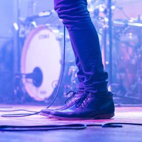 Photo of performers feet in boots on stage, drum kit in background