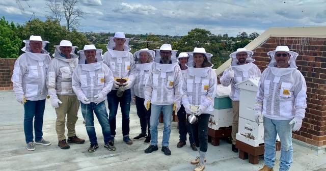 group of people in beekeeping suits