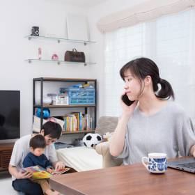 Woman using a phone, with man and child in background reading a book