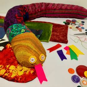 Colourful material snake with buttons and sewing items around 