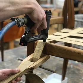 Hand and tools repairing a chair