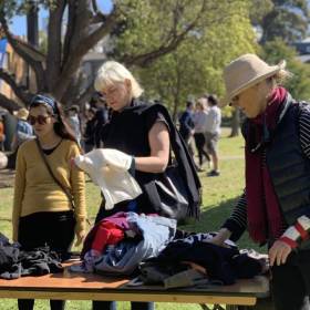 Three women leaning over a table looking at clothes