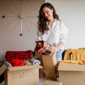 woman placing household items into two cardboard boxes