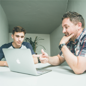 two men chatting looking at a laptop