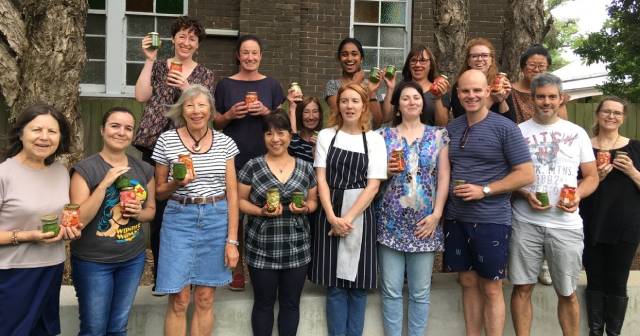 Large group people standing around holding jars of pickles