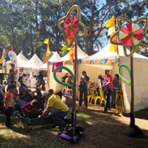 People in park with colourful tents and sculptures