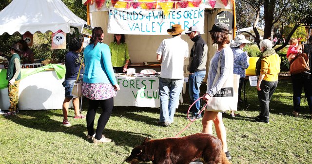 people at festival marquees and woman walking dog