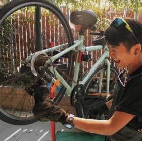 woman smiling and fixing bike wheel