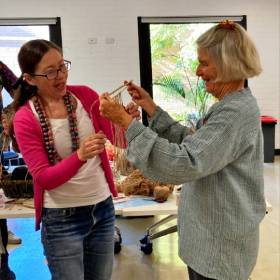 two people talking and holding string weaving