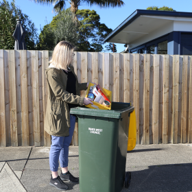 Woman putting recycling into a yellow-lidded bin