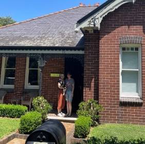 two people standing in front of large brick house