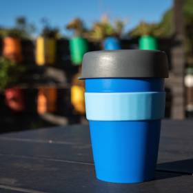 Blue reusable coffee cup sitting on table