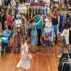 large hall filled with racks of clothing and people walking around