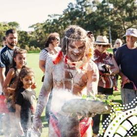 First nations man performing smoking ceremony in crowd of people