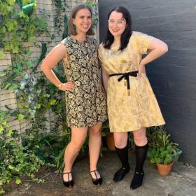 Two women standing next to each other wearing sparkly clothes and posing for the camera