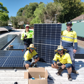 Four men installing solar panels on a roof