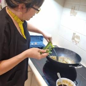 woman standing over induction stove cooking on wok