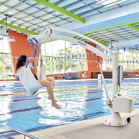 Photo of a woman with long brown hair in a pool hoist being lifted into a 50m pool