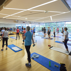 Group of people inside a group fitness studio standing holding weights