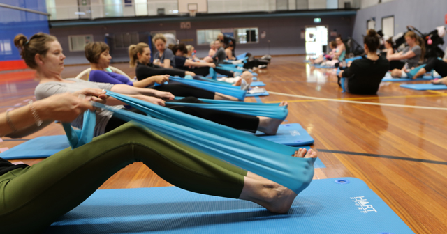 Group of parents doing pilates on an indoor basketball court