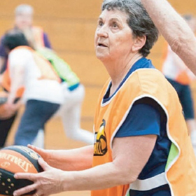 Senior holding a basketball wearing an orange team bib