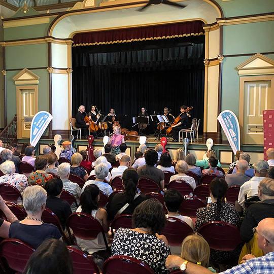 Wide shot of an audience watching an orchestra on stage