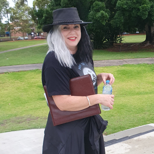 A person dressed in all black, with striking/contrasting white and black hair.