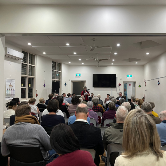 A seated group of participants at a workshop event in a small hall.