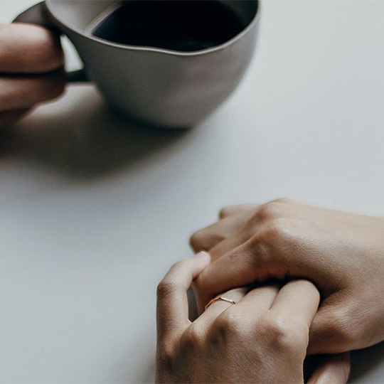 The hands of two people having a discussion across a table.