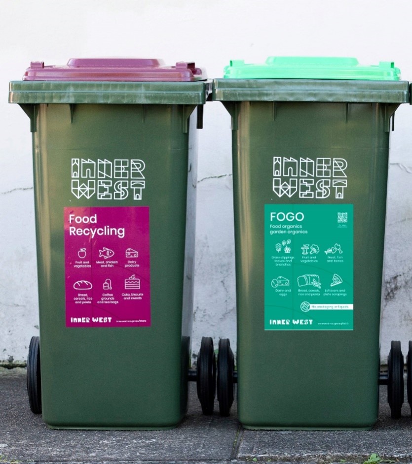 A maroon Food Recycling wheelie bin next to a green FOGO wheelie bin