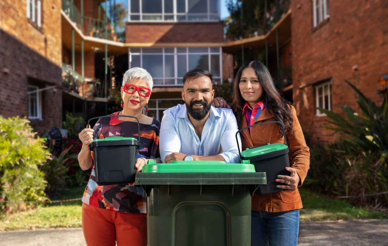 three community members standing in front of an apartment holding FOGO benchtop bins