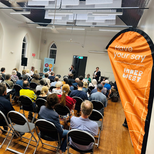 A group of people assembled in a small hall. A sign nearby reads 'Have your say - Inner West'