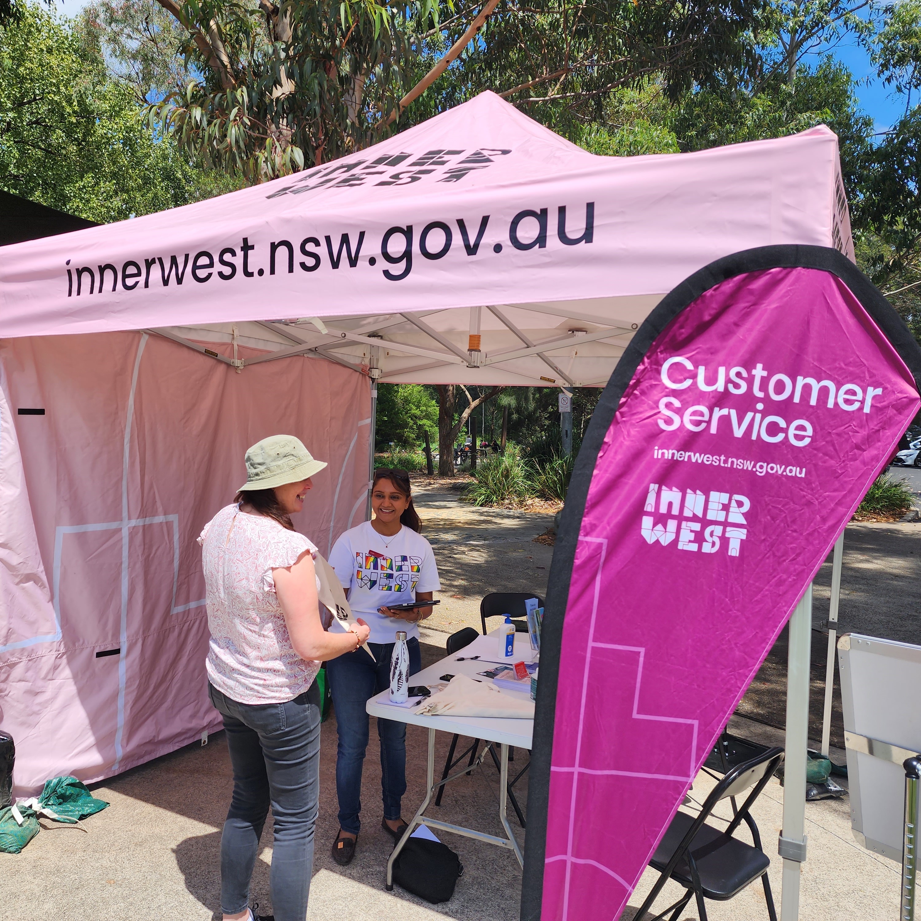 A staffed gazebo labelled with 'Customer Service' and the Inner West Council website address at an urban park.