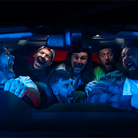 a blue image of four guys inside a car