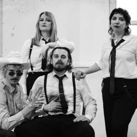 Four people, sitting and standing. Black and white image.