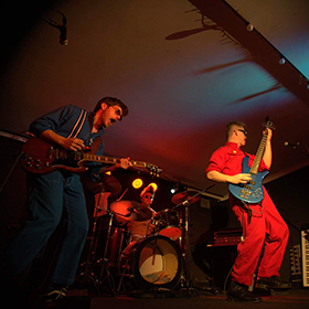 three young men on stage playing in a band